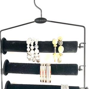 May include: Black metal jewelry hanger with six velvet-covered rods for storing bracelets. The hanger has a hook at the top and the brand name "XENA" is printed on the top bar.