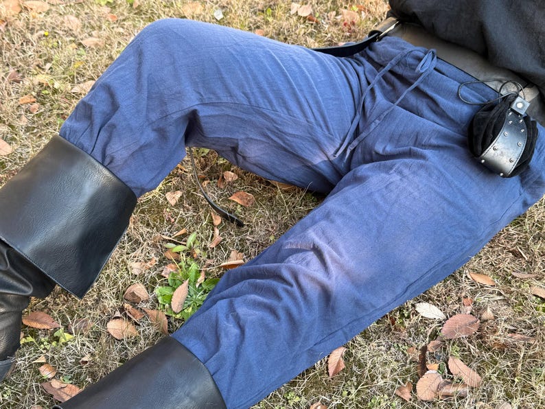 Puede incluir: Un pantal&oacute;n de algod&oacute;n azul con cintura de cord&oacute;n y cintur&oacute;n de cuero negro. El pantal&oacute;n lo lleva puesto una persona sentada en el suelo, con las piernas del pantal&oacute;n dobladas hacia arriba.