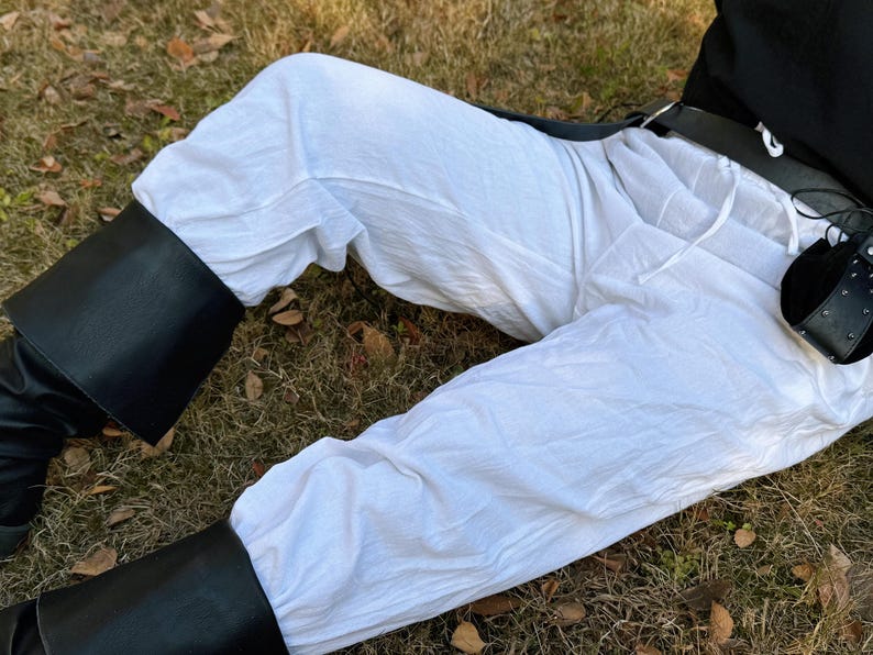 Puede incluir: Pantal&oacute;n blanco de lino con cintur&oacute;n de cuero negro y bolsa de cuero negro. El pantal&oacute;n es holgado y tiene cintura con cord&oacute;n.