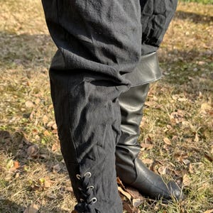Puede incluir: Pantalones negros con un detalle de encaje en la parte inferior, usados con botas de cuero negro.