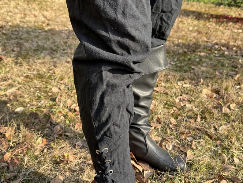 Puede incluir: Pantalones negros con un detalle de encaje en la parte inferior, usados con botas de cuero negro.