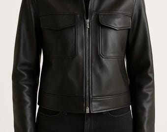 Op de afbeelding: Zwarte leren jas met een kraag, twee voorzakken en een zilveren ritssluiting. De jas wordt gedragen over een zwarte top en gecombineerd met een zwarte jeans. Een klassiek en veelzijdig bovenkledingstuk.