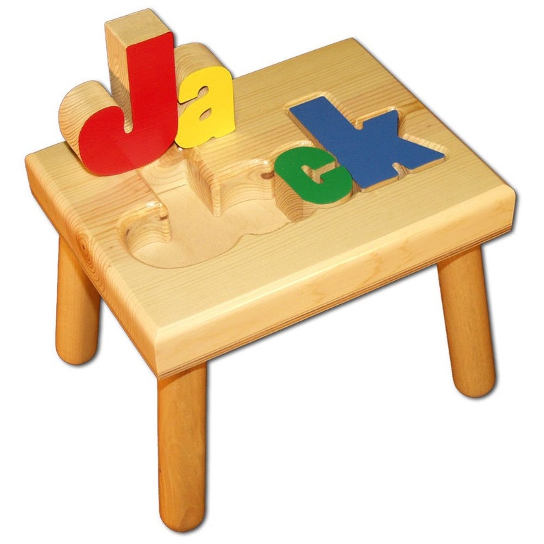 May include: A wooden stool with four legs and a cutout of the name "Jack" on the top. The letters are painted in red, yellow, green, and blue and can be removed and replaced.