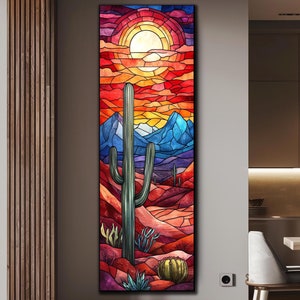 May include: A colorful stained glass style artwork depicting a desert landscape with a large cactus in the foreground. The sky is a vibrant red and orange with a large sun in the center. The mountains in the background are blue and purple.