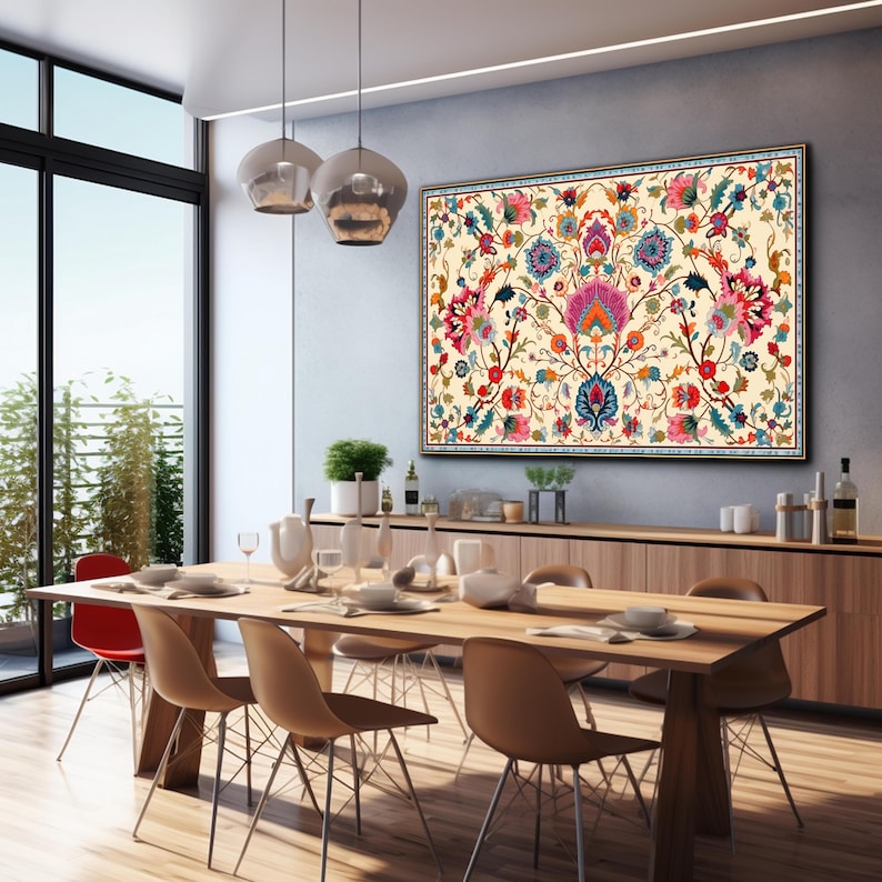 May include: A large, framed floral tapestry with a cream background and a vibrant display of pink, blue, and red flowers. The artwork hangs above a wooden sideboard in a dining room setting, with a long wooden table and chairs.