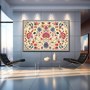 May include: Large framed floral tapestry with a cream background. The tapestry features a symmetrical design with vibrant pink, blue, orange, and green flowers and foliage. The frame is dark brown. The artwork is displayed in a modern living room.