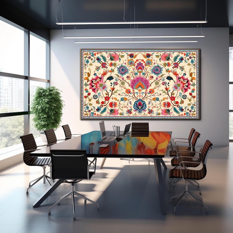 May include: A large framed floral tapestry with a cream background and a symmetrical design featuring pink, blue, red, and orange flowers. The tapestry hangs above a conference table with black chairs in a modern office setting.