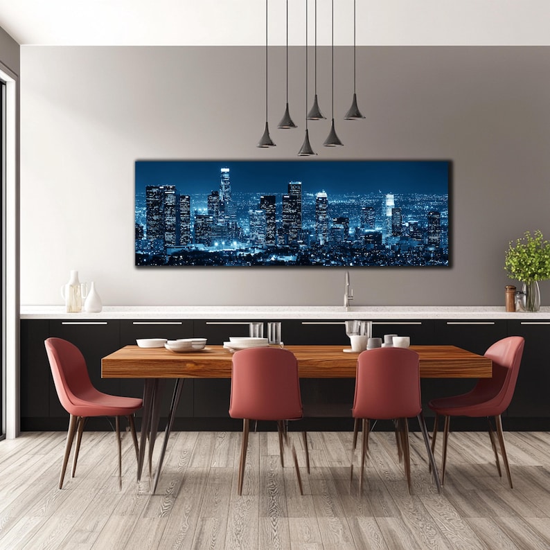 May include: A panoramic canvas print of a cityscape at night, illuminated in shades of blue. The artwork hangs above a wooden dining table with red chairs, creating a modern interior design.