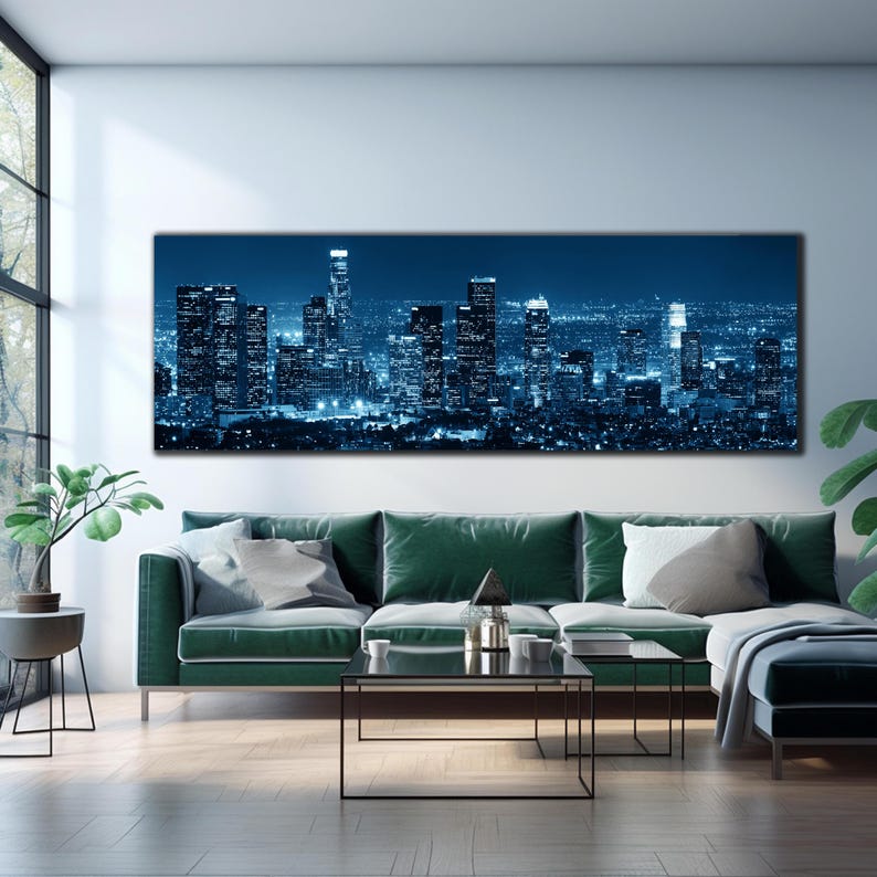 May include: A large rectangular canvas print depicting a nighttime cityscape in shades of blue. The image showcases illuminated skyscrapers and city lights against a dark sky. The artwork is displayed above a green sofa in a modern living room setting.