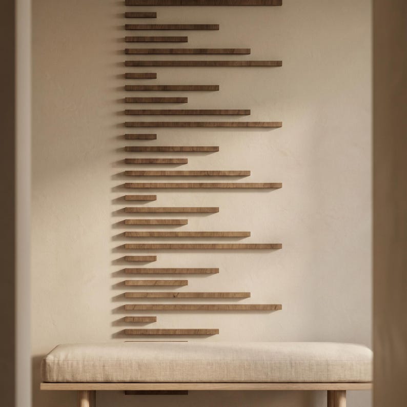 May include: A modern interior scene featuring a series of wooden shelves arranged in a linear pattern on a light-colored wall. Below, a bench with a neutral-toned cushion and wooden frame provides seating. The design creates a minimalist, contemporary aesthetic.