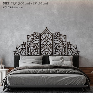 May include: A dark brown wooden headboard with an intricate design, 200 cm wide and 90 cm high, is mounted above a bed with grey bedding. The headboard is Palisander in colour.