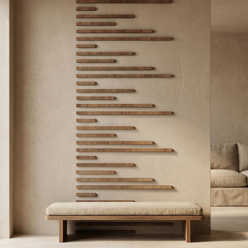 May include: A modern interior scene featuring a wooden bench with a beige cushion. Above the bench, a series of horizontal wooden planks are mounted on a beige wall. The planks vary in length and create a unique design element. A sofa is visible in the background.