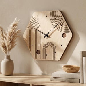 May include: A wooden wall clock with a geometric hexagonal design. The clock face is light wood, featuring black lines and dots in an abstract pattern. The clock hands are black. The clock is mounted on a beige wall.