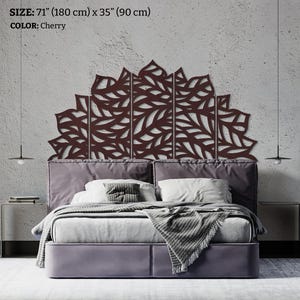 May include: A cherry-coloured, laser-cut metal headboard with a leaf design, measuring 180 cm wide and 90 cm high. The headboard is above a bed with a grey upholstered frame, pillows, and a blanket. The text on the image says: SIZE: 71" (180 cm) x 35" (90 cm) COLOR: Cherry.