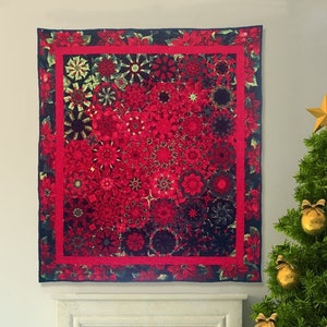 May include: A rectangular quilt featuring a repeating pattern of red poinsettia flowers on a dark background. The quilt is framed by a solid red border and an outer border of poinsettia prints, creating a vibrant, floral-themed textile piece.