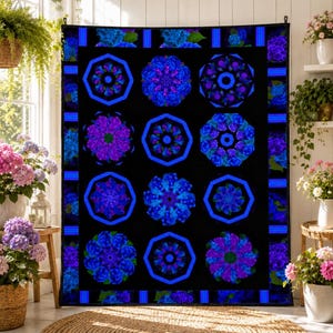 May include: A black quilt featuring a repeating floral pattern in shades of blue and purple. The design includes octagonal frames around each floral motif, with a blue border. The quilt is displayed indoors.
