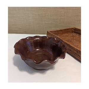 May include: A brown ceramic bowl with a scalloped rim. The bowl is empty and has a glossy finish.