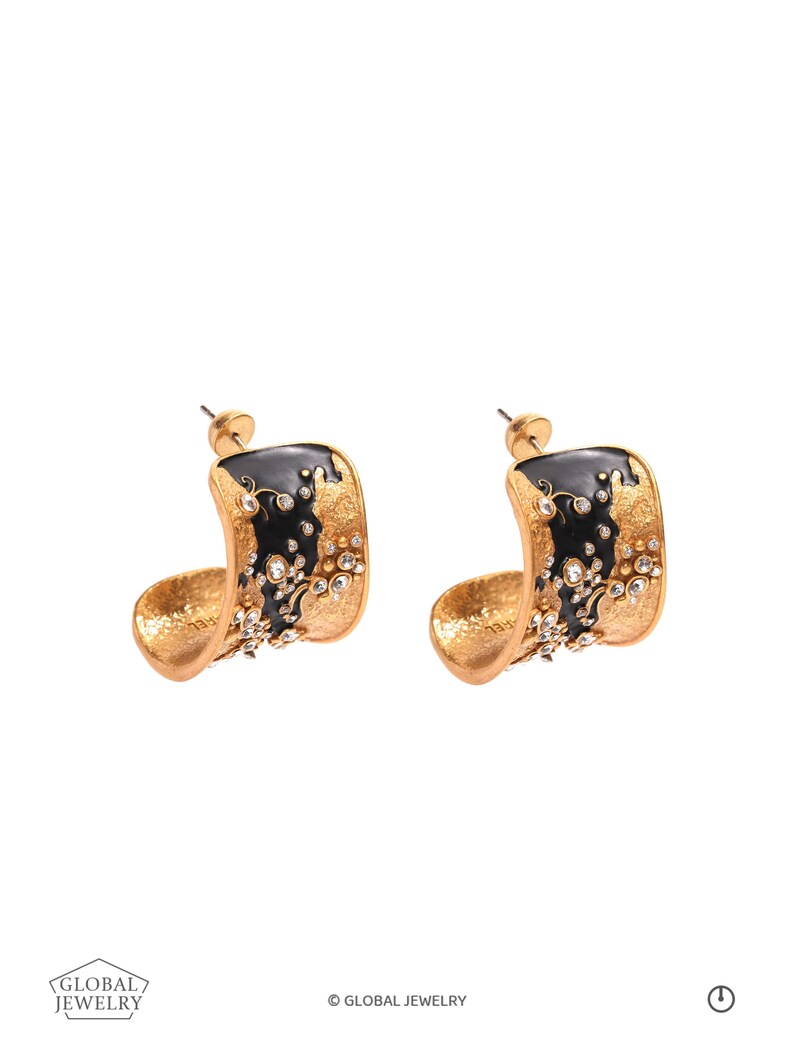May include: A pair of gold-toned hoop earrings with a black enamel design and sparkling crystal accents. The earrings have a curved, open design and are set against a white background. The earrings are from Global Jewelry.