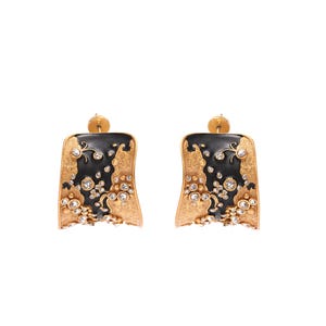 May include: A pair of gold-toned earrings with a black enamel design and sparkling clear gemstones. The earrings have a rectangular shape with a curved edge and a post backing. The design includes floral and abstract elements.