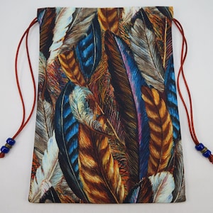 May include: A drawstring bag with a red cord and blue beads. The bag is made of fabric with a colorful feather pattern in shades of brown, blue, and white.