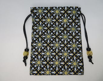 May include: A black drawstring bag with a repeating pattern of gold and light blue starbursts on a black background. The bag has a black drawstring closure with gold and black beads. This bag is suitable for small items.