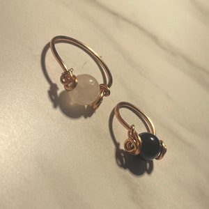 May include: Two gold wire rings with a white and a black bead. The rings are simple and elegant.