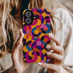 Op de afbeelding: Een kleurrijke telefoonhoes met een geometrisch patroon van cirkels en vierkanten in tinten roze, geel, blauw en zwart.