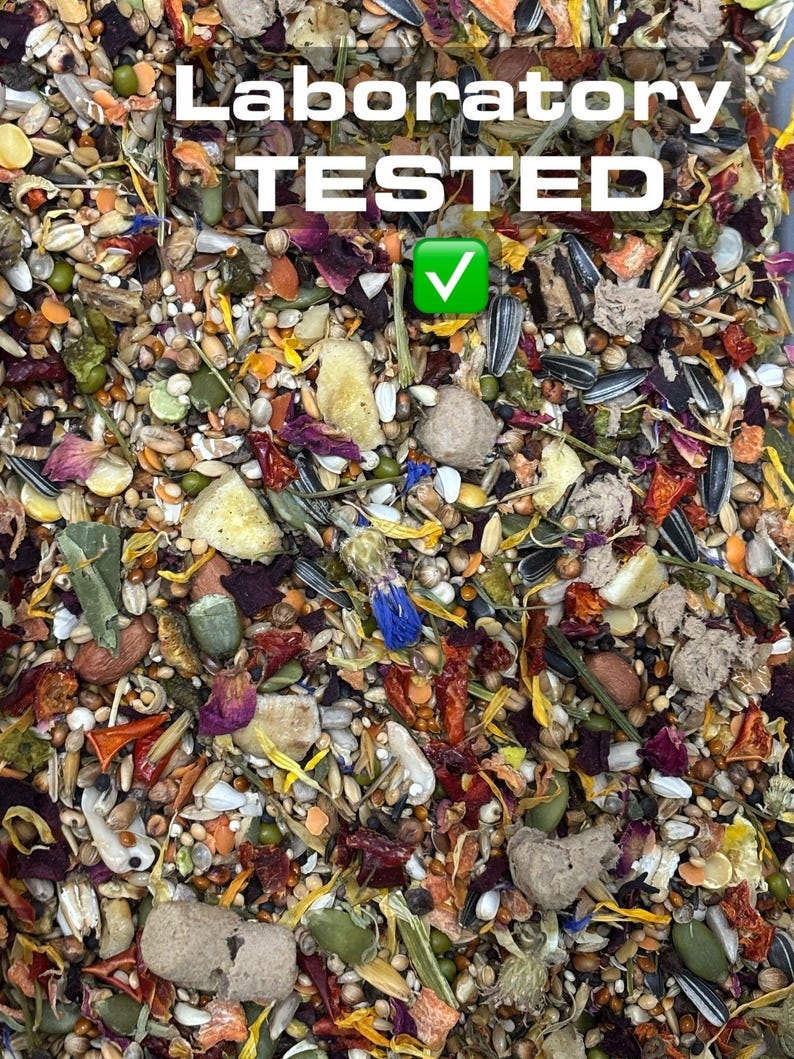 Puede incluir: Primer plano de una mezcla de semillas, granos y flores secas. La imagen est&aacute; etiquetada como "Laboratory TESTED" con una marca de verificaci&oacute;n verde. La mezcla incluye semillas de girasol, semillas de calabaza y otros ingredientes.