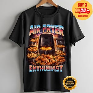 Könnte beinhalten: Ein schwarzes Kurzarm-T-Shirt mit einem Grafikdruck einer Heißluftfritteuse, umgeben von verschiedenen frittierten Lebensmitteln wie Hähnchenflügeln und Pommes frites. Der Text AIR FRYER steht darüber und ENTHUSIAST darunter.