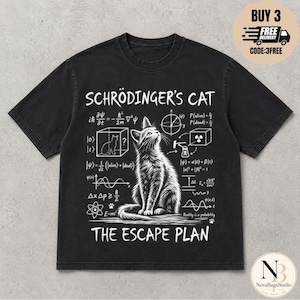 May include: A black short-sleeved t-shirt featuring a white graphic print of a cat sitting in the centre. The design includes the text "SCHRÖDINGER'S CAT" and "THE ESCAPE PLAN" surrounded by various physics equations, diagrams, and scientific symbols.