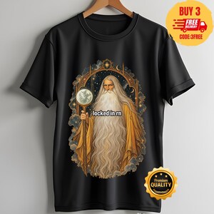 Könnte beinhalten: Ein schwarzes Kurzarm-T-Shirt mit einer Grafik eines langbärtigen Zauberers in goldenen Gewändern, der eine leuchtende Kugel in einem verzierten Torbogen vor einem Sternenhimmel hält, mit dem Text "locked in rn" in der Mitte des Bildes.