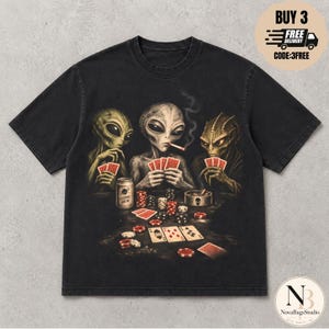 Könnte beinhalten: Ein schwarzes Kurzarm-T-Shirt mit einem Grafikdruck von drei außerirdischen Wesen, die an einem Tisch ein Kartenspiel spielen. Das Design zeigt Spielkarten, Stapel aus roten und schwarzen Pokerchips, eine Getränkedose und einen Aschenbecher.