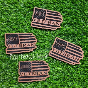 May include: Four brown leather American flag patches with the words "Army Veteran", "Navy Veteran", "USMC Veteran", and "Air Force Veteran" printed in black.