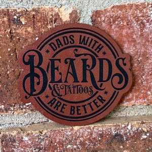 May include: A brown leather patch with black text that reads "Dads with Beards & Tattoos are Better".