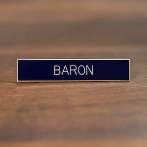 May include: A navy blue name tag with the word "BARON" printed in white.