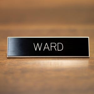 May include: A black metal nameplate with the word "WARD" engraved in white lettering.