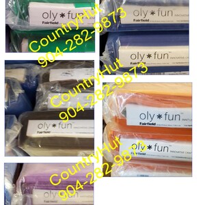 May include: A close-up of several packages of fabric in various colors, including green, blue, orange, brown, and purple. Each package has a label that reads "oly * fun" and "Fairfield". The phone number "904-282-9873" is printed on the label.