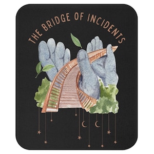 May include: Black mousepad with a watercolor illustration. The design features a bridge held by two gray hands, with the text "THE BRIDGE OF INCIDENTS" in a brown font. The bridge is brown, and the background is black.