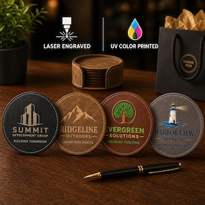 May include: Four circular faux leather coasters featuring custom designs: a black coaster with Summit Development Group text, a tan coaster with Ridgeline Outdoors text, a brown coaster with Evergreen Solutions text, and a gray coaster with Harbor View Financial text.