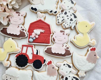 May include: A set of farm animal-themed sugar cookies, including a red barn, a tractor, a pig, a cow, a sheep, a duck, and a chicken. The cookies are decorated with colorful icing and details.
