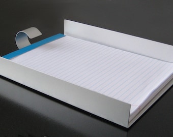 May include: A silver metal notepad holder with a blue clip. The holder is empty and ready to hold a notepad.