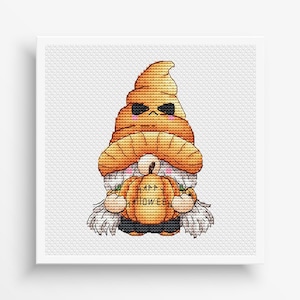 May include: A cross-stitch design of a Halloween gnome. The gnome wears a pumpkin-shaped hat and holds a pumpkin with the words "Happy Halloween" on it. The gnome has a white beard and is set against a white background.