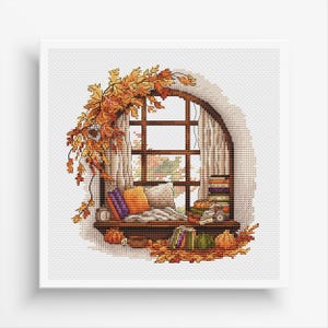 May include: A cross-stitch pattern depicting a cosy window seat with a stack of books, a throw pillow, and a view of autumn leaves. The window is framed by a garland of autumn foliage.