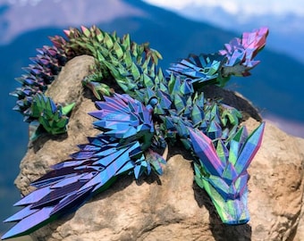 May include: A iridescent blue, green, and purple dragon sculpture made of faceted crystals. The dragon is perched on a rock with a mountain background.