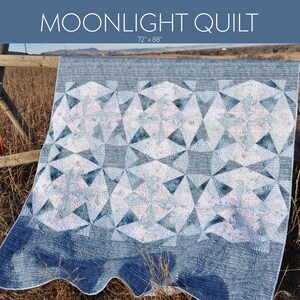 Könnte beinhalten: Ein Quiltmuster namens "Moonlight Quilt", entworfen von Sherri Noel, mit der Stoffkollektion "Brushstrokes" von shell rummel. Der Quilt ist 72 Zoll mal 88 Zoll groß und aus einem blauen und weißen Stoff mit geometrischem Muster gefertigt.