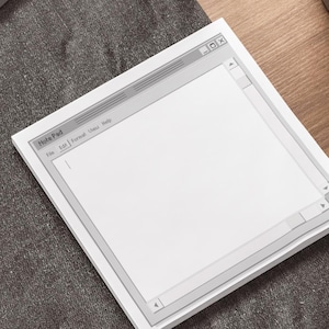 May include: A white notepad with a gray border, resembling a computer window, with the text "Text Pad" at the top. The notepad is on a gray surface.