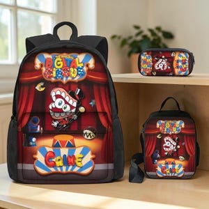 May include: A black backpack, a lunch bag, and a pencil case featuring The Amazing Digital Circus theme. Each item displays a red curtain stage, a cartoon character with large teeth, and the text The Amazing Digital Circus and Caine.
