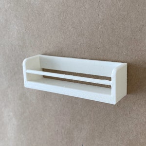 May include: White plastic shelf with two shelves. The shelf is mounted on a wall.