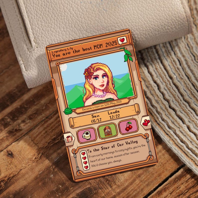 Może przedstawiać: Cyfrowa ilustracja kobiety z blond włosami i r&oacute;żowym kwiatem we włosach. Ilustracja jest w pikselowym stylu, podobnym do gry wideo Stardew Valley. Tekst głosi "Legendary Lily You are the best MOM 2025" i "Became a mom on 12th May 2020". Ilustracja jest otoczona brązową ramką z ikoną serca w prawym g&oacute;rnym rogu.