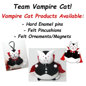 May include: Three plush vampire cat ornaments. The cat is white with black eyes, red fangs, and a black cape. The cat is wearing a black waistcoat with a white button. The cat is holding a red cape in its paws. The text "Team Vampire Cat!" and "Vampire Cat Products Available:" is at the top of the image. The text "Hard Enamel pins", "Felt Pincushions", and "Felt Ornaments/Magnets" is below the image of the cat.